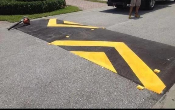 Asphalt speed bump finished with reflective yellow chevron striping for visibility