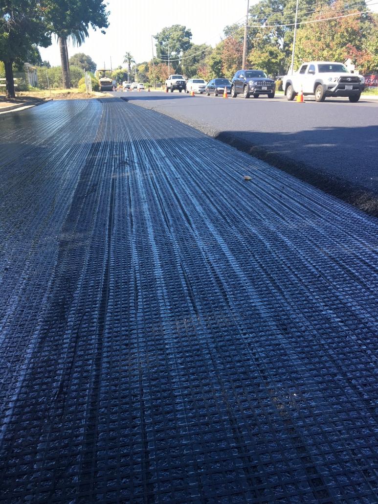 Pavement reinforcement geogrid mesh laid across a road surface in Northern Virginia before the new asphalt overlay is placed on top