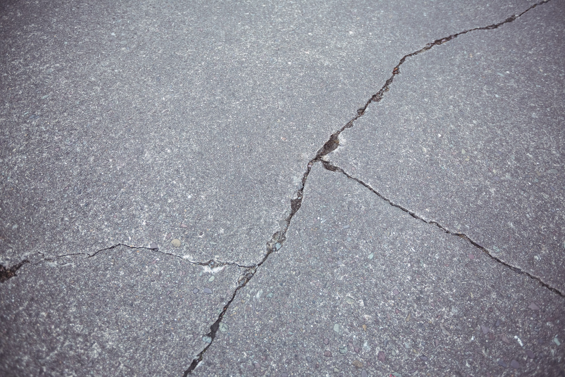 Close-up of cracked, uneven asphalt showing signs of a sinking driveway