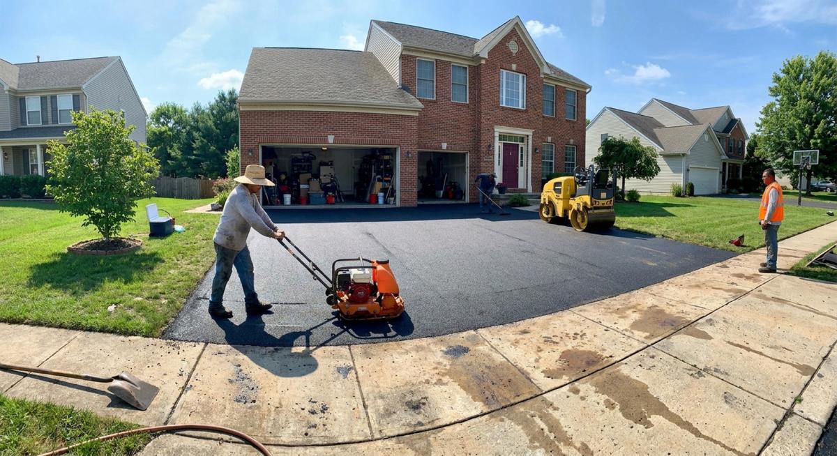 Road reconditioning project — a crew compacting a freshly repaved surface with rollers and plate compactors